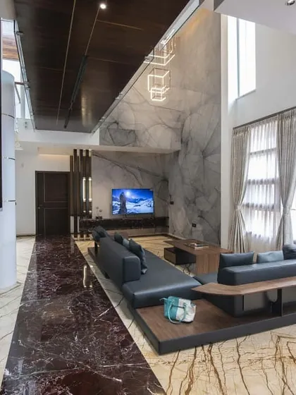 The living area of this residence is defined by its bold use of materials, including two types of striking marble on the floor and a textured grey marble for the entertainment wall. The low-slung sofa maintains the open, spacious feel.