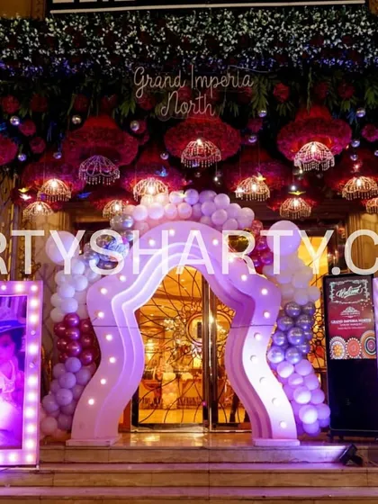 An opulent entrance for a butterfly princess theme, featuring a lit archway, hanging floral arrangements, and large, illuminated photo frames of the birthday girl.