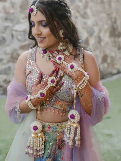 The bride looks stunning in her multi-coloured lehenga and our custom floral jewellery. The purple accents in the flowers tie the whole look together.