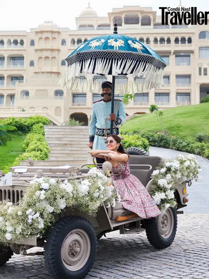 A playful moment from the Condé Nast Traveller shoot. We styled this shot with a vintage jeep adorned with baby's breath, showcasing a fun and stylish baraat entrance idea for the modern bride.