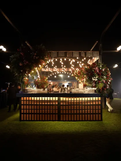 The magnificent island bar we designed for the "Golden Rails" event. The backlit wooden base, string bulb canopy, and lush floral arrangements made it a central hub of the celebration.