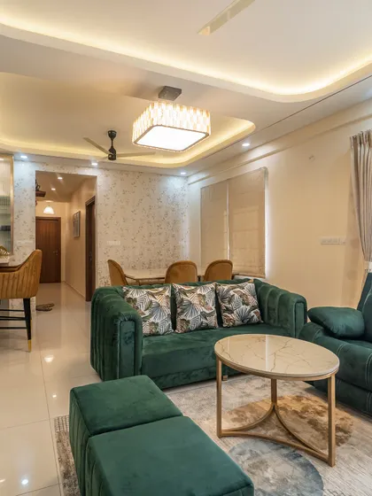 An inviting living area featuring an emerald green sofa that adds a pop of color. The space is designed for comfort and conversation, with a layout that connects seamlessly to the kitchen's breakfast bar and the dining area.