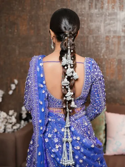 I love adding a modern twist to traditional hairstyles. This stunning silver-accented braid is a perfect example, designed to complement the rich blue hues of the lehenga. It's a unique and elegant statement for any bridal function.