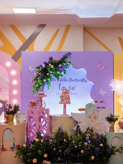 A full view of a whimsical butterfly and fairy-themed first birthday. The design combines pastel balloon garlands, light-up arches, and adorable fairy cutouts to create a soft, dreamy, and magical atmosphere.