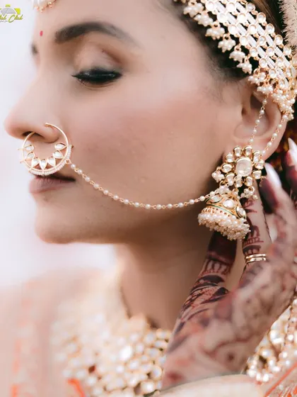 A stunning close-up on the bride's traditional jewelry. This detail shot highlights the intricate nath and jhumka, essential elements of the Indian bridal look.
