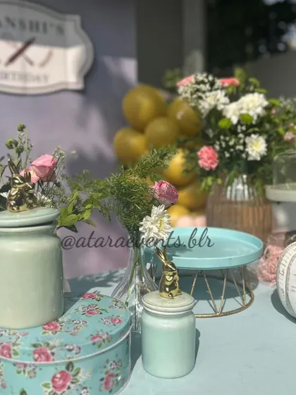 A close-up of the decor at a pizza-making party. The table is set with floral arrangements in vintage-style jars, adding a touch of rustic charm to the creative theme.