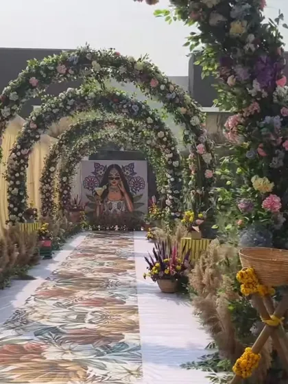 A beautiful floral archway leading into a Haldi ceremony. The aisle is decorated with a printed floral runner, setting a whimsical and welcoming tone.