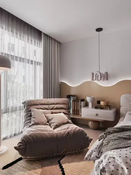 A cozy and modern bedroom corner featuring a comfortable lounge chair and a unique wavy headboard with backlighting. This design shows how we create relaxing nooks within a larger space.