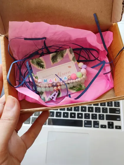 A peek inside our gift packaging for a custom name bracelet set. We use bright tissue paper to make unboxing a fun experience.