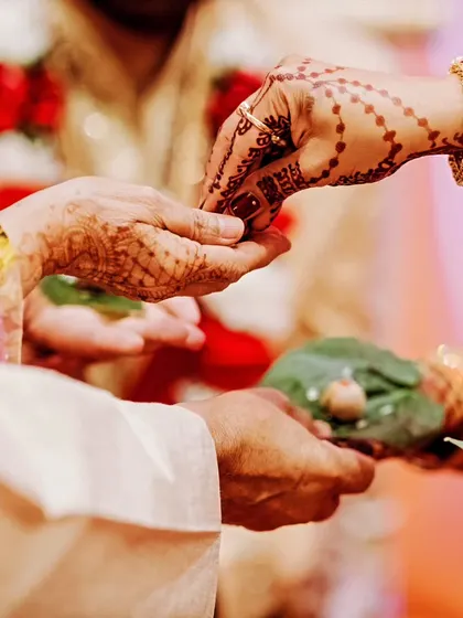A close-up of a ritual during the wedding ceremony, focusing on the hands and the sacred offerings.