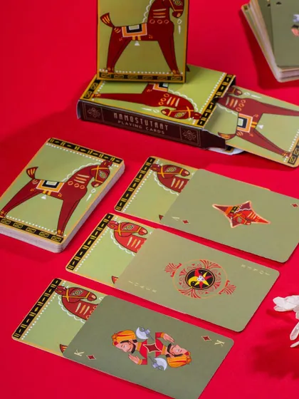 A colorful display of Namostutay playing cards with a horse motif. The bold red and green color scheme is energetic and eye-catching.