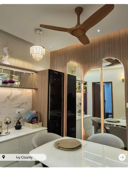 A dining area that feels open and connected to the living space. The design uses wood paneling, mirrors, and a modern chandelier to define the space beautifully.