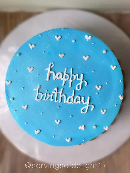 A simple and sweet blue birthday cake dotted with tiny white hearts. It's a minimalist design that's full of charm.
