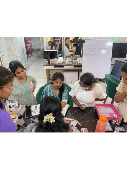 A trainer giving personalized guidance to a small group of students during a hands-on nail art session.