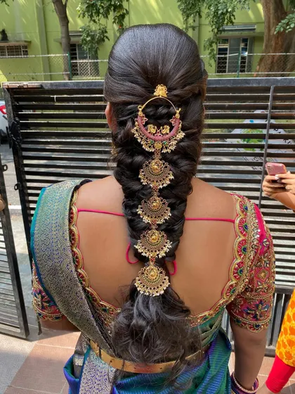 A stunning messy braid adorned with a full set of traditional temple jewelry, perfect for a bride on her engagement day.