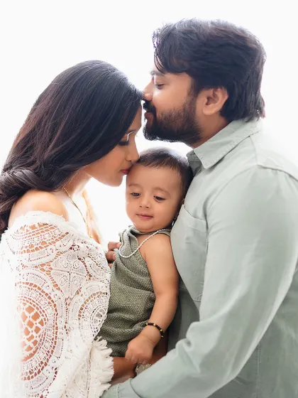 A tender moment with both parents kissing their baby's head.