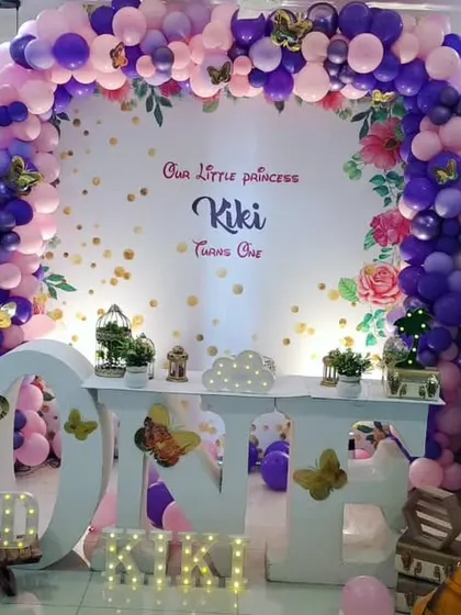 We created this lovely butterfly and princess theme for Kiki's first birthday. A purple and pink balloon arch frames the backdrop, with a large "ONE" table and butterfly accents throughout.