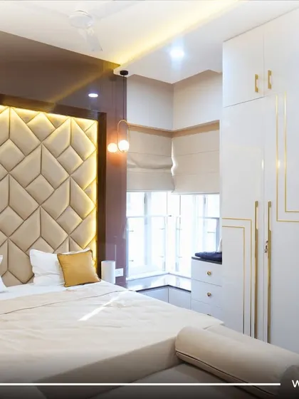 High-gloss white wardrobes with gold trim reflect light beautifully, making this bedroom feel bright, spacious, and undeniably glamorous.
