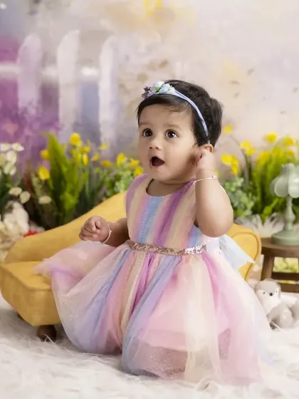 A rainbow of colors for a beautiful little girl. Her pastel rainbow dress looks stunning against the soft, painterly flowers of our garden-themed backdrop.