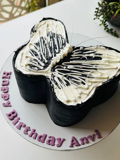 A unique butterfly-shaped cake in black and white. The abstract buttercream design on the wings creates a modern and artistic look.
