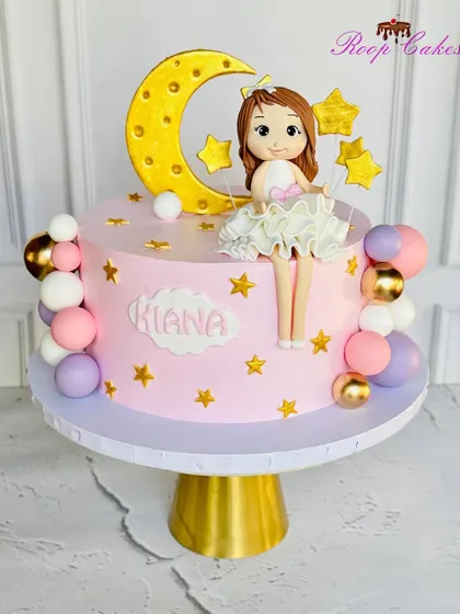 Under the moon, a little star shines bright. This cake features a sweet doll sitting on a crescent moon, surrounded by stars and colorful spheres.