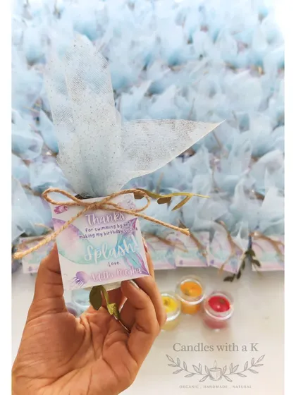 Holding the personalized thank you tag from the mermaid-themed birthday favors, which reads "Thanks for swimming by!"