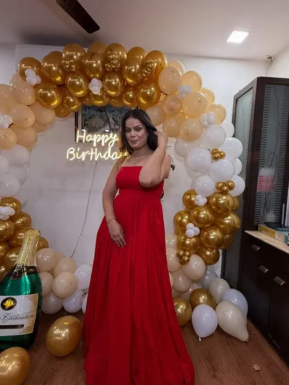 The birthday girl posing in front of her decorations. Her hair and makeup look glamorous and party-ready.