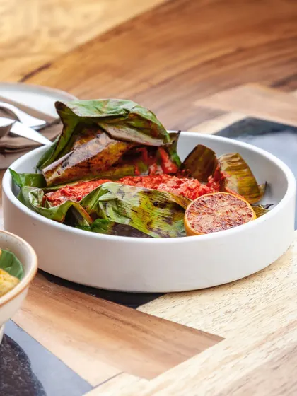 Bhetki fish marinated in a fiery red masala, wrapped in a banana leaf and steamed. The leaf imparts a subtle, earthy aroma to the tender fish.