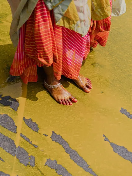 A detail shot of the Laheriya skirt against the haldi-stained floor, a beautiful collision of color and tradition.