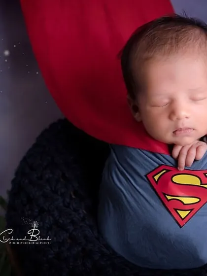 A close-up of our little Superman, complete with the famous 'S' logo and a flowing red cape. He looks ready to save the world in his sleep.