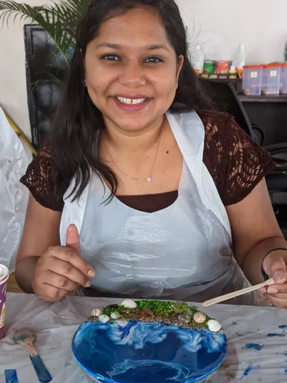 A smiling participant with her completed resin beach art. The workshop is a great way to unwind and create something beautiful.