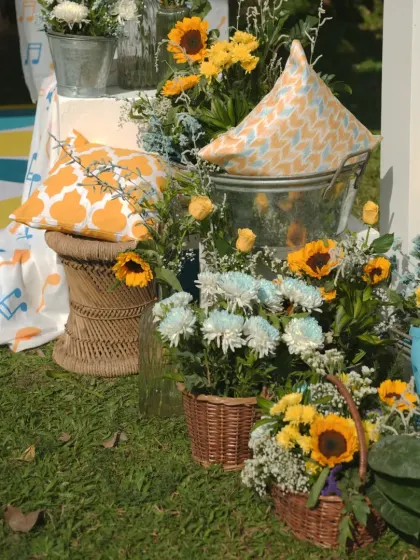 A corner of the "Dhobi Ghat" Haldi setup, with wicker baskets of sunflowers, printed cushions, and colorful fabrics creating a rustic and cheerful look.