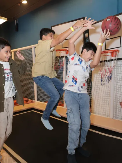 Two boys leap into the air to make a basket on our trampoline basketball court.