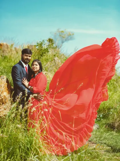 A dynamic pre-wedding portrait with the bride's flowing red dress creating a heart-like shape against the open landscape.