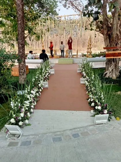 The entrance aisle for a day wedding, lined with beautiful white and green floral arrangements, leading guests to the main event area.