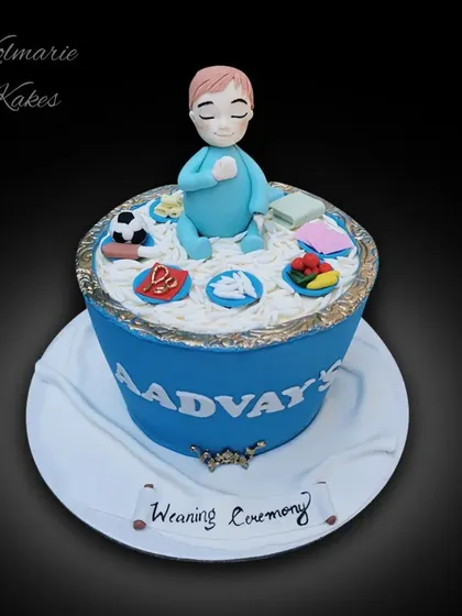 A special cake for a baby's weaning ceremony. The design represents the traditional rice feeding ceremony, complete with a fondant baby and symbolic items. The flavor was vanilla with blueberry frosting.