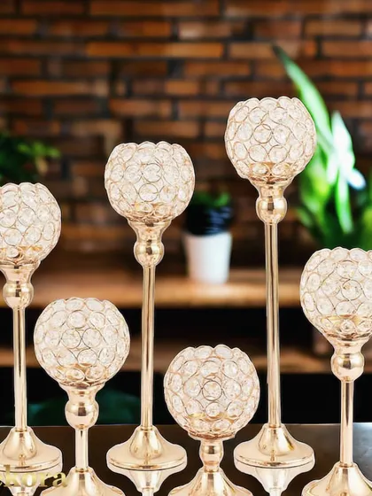 An elegant set of crystal T-light candle holders of varying heights. The sparkling crystal globes on slender gold-finish stems create a dazzling effect, perfect for festive home decor.