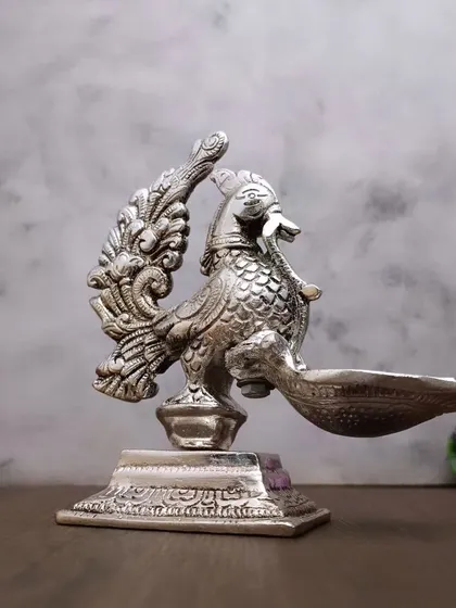 A side view of the antique German silver peacock diya, showcasing its intricate feather details and graceful posture.