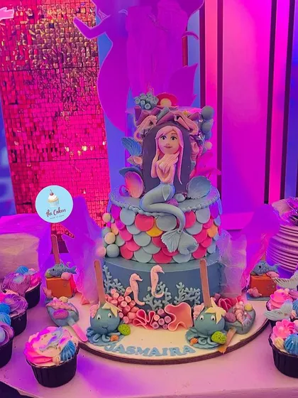 A full view of the mermaid-themed dessert table, featuring the grand tiered cake, piñata cake, and matching cupcakes.
