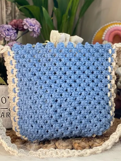 This powder blue shoulder bag is perfect for a soft, dreamy look. It has a secure drawstring closure and a contrasting off-white strap and border.