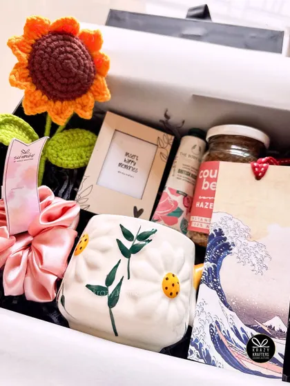 Sending some sunshine for her birthday! This hamper features a crochet sunflower, a daisy-themed mug, a 'smells like sunshine' candle, and other cheerful goodies.