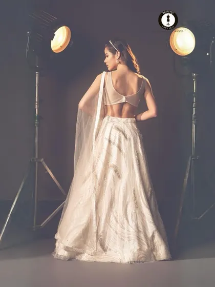 The back of this ivory lehenga is just as stunning as the front, featuring a sheer panel and delicate detailing for a touch of modern allure.