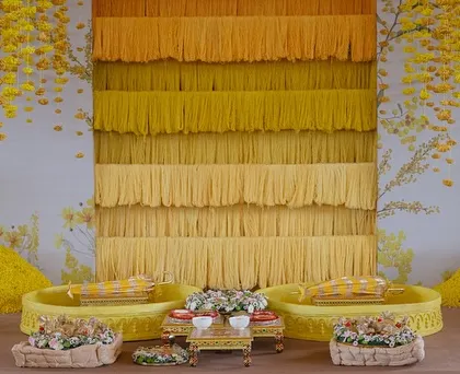 A close-up of the ombre yellow thread backdrop, a unique and modern take on traditional Haldi decor.