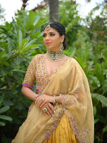 A closer look at the gold and purple half saree, showing the intricate details of the blouse and the beautiful braid of the model.