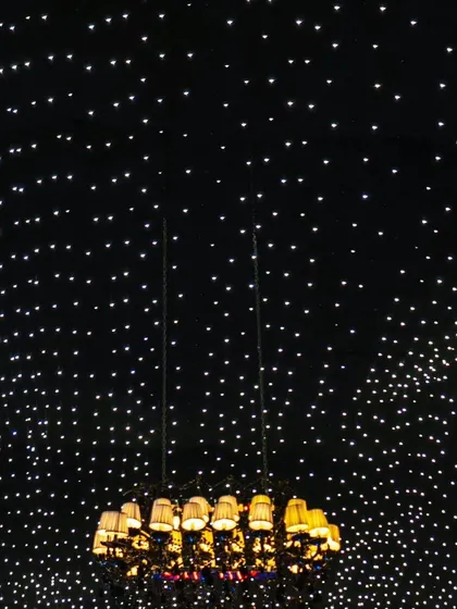 Looking up at the vast expanse of the starlit ceiling, with a grand chandelier appearing to float in a galaxy of lights.