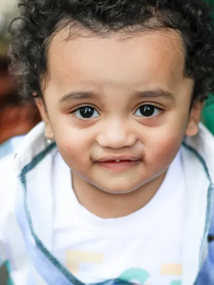 A close-up portrait of a toddler with an endearing, gentle smile. His expressive eyes and curly hair are the details that make this shot so special.