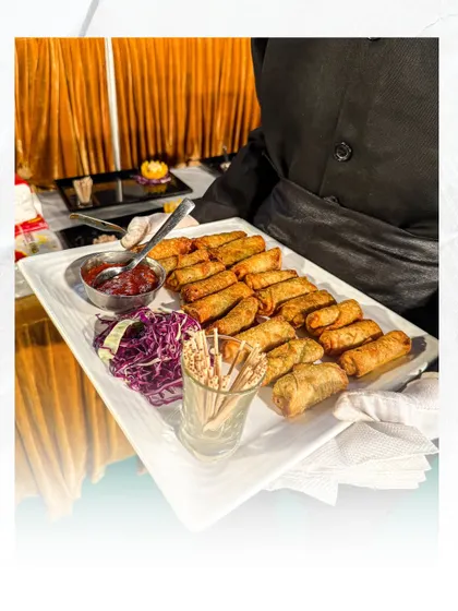A server holds a tray of freshly prepared spring rolls. This classic appetizer is a staple at many events, and we ensure ours are crispy, flavourful, and served with the perfect dipping sauce.