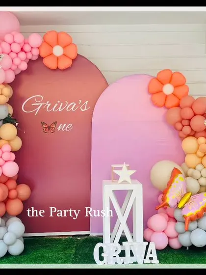 Griva's butterfly-themed first birthday featured this beautiful balloon arrangement in warm shades of pink, orange, and yellow. The arched backdrops and butterfly accents create a modern and cheerful look.