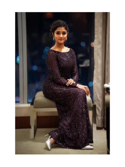 A full-length seated portrait that feels both graceful and poised. The composition uses the window and city view to add context and a sense of urban sophistication.