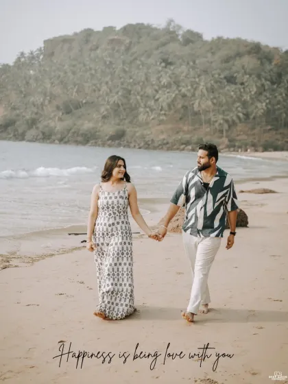 A happy, candid shot of a couple walking hand-in-hand on the sand, their smiles reflecting the joyful and relaxed atmosphere of a Goa pre-wedding shoot.